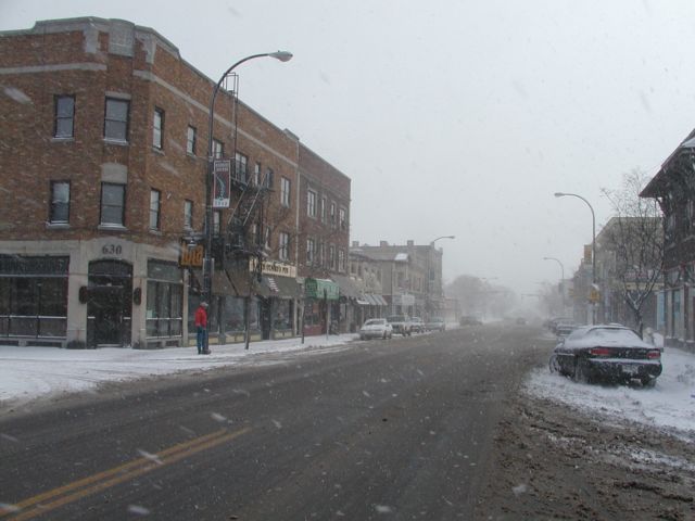 Photo winter snow flies on Monroe Ave. View looking east, Lola Bistro & Bar on the left with a man waiting on the corner for the RTS bus. Snow covered Rochester NY New York City living January 23rd 2003 POD I Love NY Rochester NY New York Picture Of The Day view picture photo image pictures photos images, January 23rd 2003 POD