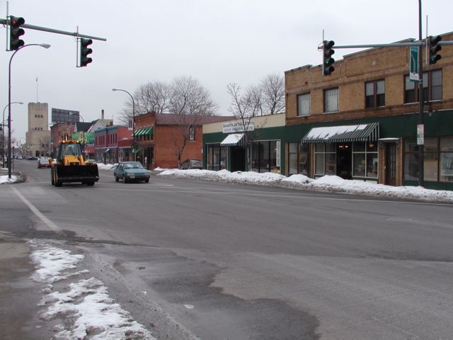 Picture The former Sears and Roebuck Company Monroe Ave store is the tall, light brown, building with flagpole in upper left of photo. A frontend loader makes it's way past the numerous shops that line the busy street. Rochester NY winter view. Rochester NY March 7th 2003 POD winter Picture Of The Day view picture photo image picture pictures photos images