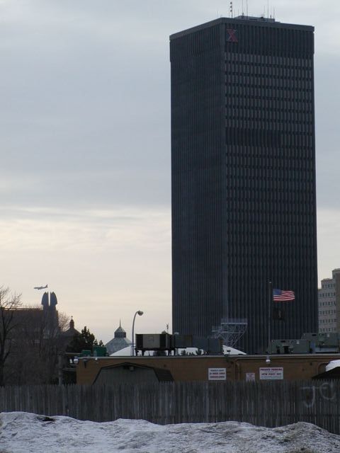 Picture A passenger jet flies over Rochester making it's way through the sky behind the Times building, while Old Glory and the Pow MIA flag flies over the Thomas F. Healy VFW Post 16 54 S. Union Street. O'er the land of the free and the home of the brave! Rochester NY winter view. Rochester NY March 12th 2003 POD winter Picture Of The Day view picture photo image picture pictures photos images