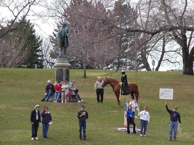 Support Our Troops. That's what the man's sign says.  A horse of the Rochester Mounted Police makes a sensible fashion statement with yellow ribbon. Some horses have more sense than humans... Image 7 of 60  -  60 kB