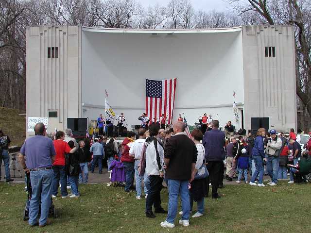 The sign says 'God Bless Our Troops' Nik & the Nice Guys entertain the crowd, those in front of the stage are writing personal messages on a 40 foot long banner meant for U.S. Troops. Rally 'Round America, Rochester NY, Highland Bowl, April 19th, 2003. Image 59 of 60  -  47 kB