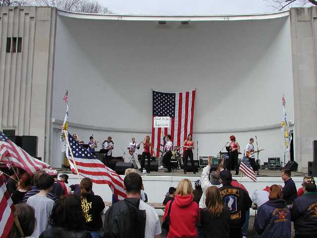 The sign says 'Proud to be American' the band on the stage is Nik and the Nice Guys, and you are viewing Americans, who are sick and tired of all the media attention focused on a vocal minority that do not speak for the vast MAJORITY of Americans who do support George W. Bush, U.S. Troops, and coalition efforts to make the world a safer, more peaceful place. Hosted by Rochester NY news radio WHAM 1180 AM, 50,000 watts heard in more than 30 U.S. States. Image 60 of 60  -  35 kB